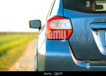 Primo piano della luce di posizione posteriore rossa e specchio della nuova auto fuoristrada SUV blu pulita su strada rurale Foto Stock