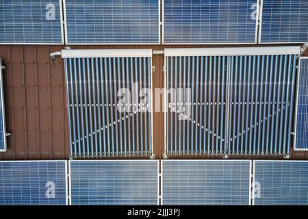 Pannelli fotovoltaici e collettori solari ad aria sottovuoto per il riscaldamento dell'acqua e la produzione di elettricità pulita montati sul tetto della casa. Produzione di Foto Stock