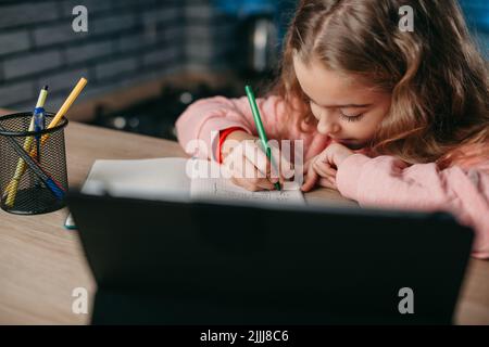 Studentessa caucasica che studia da remoto su tablet, preparandosi per l'esame a casa. Tecnologia Internet. Foto Stock