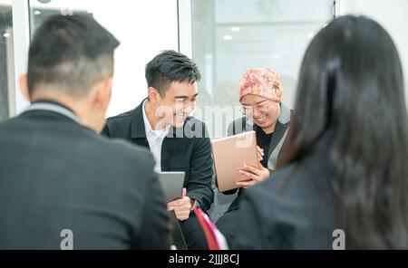 I colleghi dell'ufficio di affari ridono sopra una barzelletta mentre fanno una riunione. Cultura aziendale positiva e divertente. Foto Stock