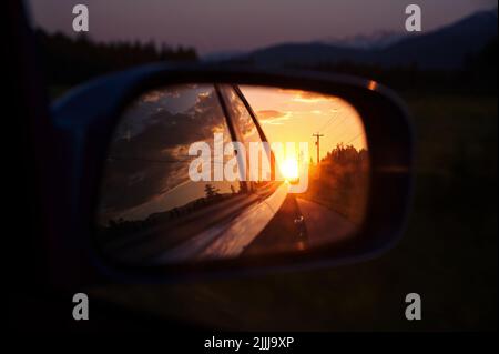 Bel tramonto in veduta laterale specchio auto sulla strada di montagna Foto Stock