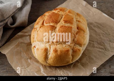 Pane di Pan rotondo casalingo del Boule su carta marrone, tavola rustica di legno. Panetteria Concept Foto Stock