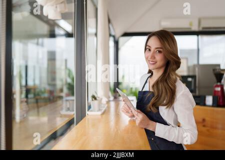 Ritratto del barista asiatico proprietario del caffè con il tablet per controllare l'ordine sme imprenditore venditore business concetto. Foto Stock