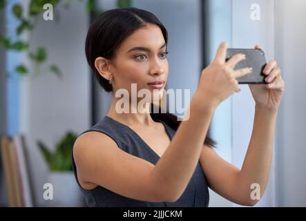 Vorrei fare una foto di questo: Una giovane donna d'affari che usa un cellulare in un ufficio. Foto Stock
