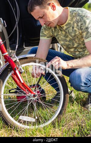 Papà pompa su gomme della bici per sua figlia. Primo piano il bel meccanico della bicicletta che pompa la ruota della bicicletta. Giornata mondiale della bicicletta. Concetto di manutenzione della bicicletta. Tecnica Foto Stock