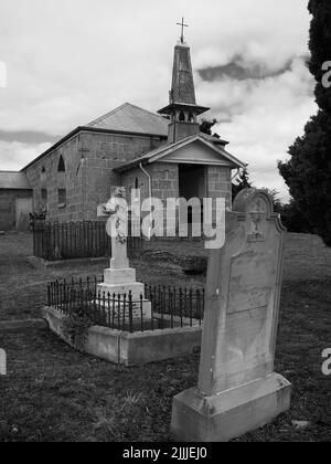 Una foto verticale in scala di grigi di una vecchia chiesa e cimitero in Ouse, Tasmania Foto Stock