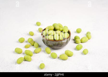 Mucchio di arachidi verdi rivestite con wasabi in una ciotola, snack piccante, cibo orientale Foto Stock