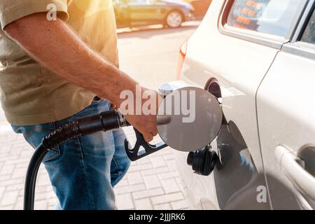 Un uomo alla stazione di benzina che riempie il serbatoio della sua auto con diesel al livello superiore prima di un lungo viaggio come i prezzi del carburante sta salendo Foto Stock