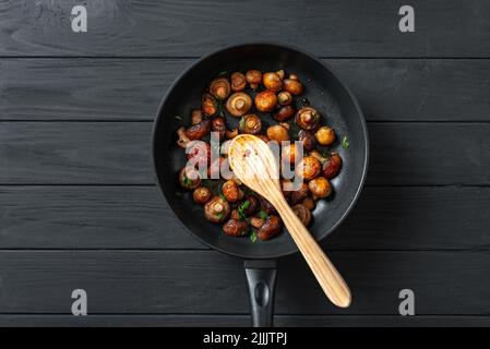 Padella di funghi fritti Champignons su sfondo di legno scuro. Vista dall'alto. Posiziona per testo Foto Stock