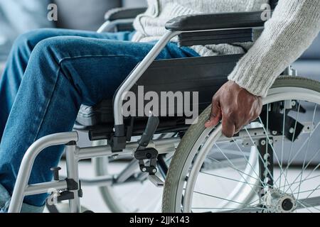 Primo piano di un uomo africano con disabilità che utilizza la sedia a rotelle per muoversi durante la sua riabilitazione Foto Stock