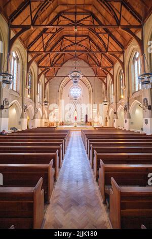 Una vista della navata centrale con ciaiette di legno e l'altare in lontananza. Alla Cattedrale Metropolitana di Cardiff, Galles, Regno Unito. Foto Stock
