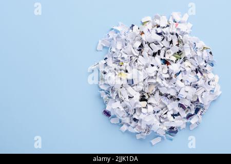 Un mucchio di documenti tagliati a croce, tagliati su sfondo blu, vista dall'alto con spazio di copia Foto Stock