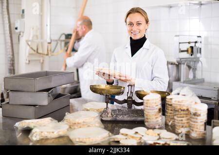 Donna in piedi con scatola di torrone in fabbrica Foto Stock