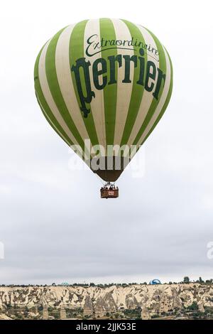 GOREME/TURCHIA - 29 giugno 2022: Mongolfiera con lettere Perrier vola sulla città di goreme. Turchia. Foto Stock