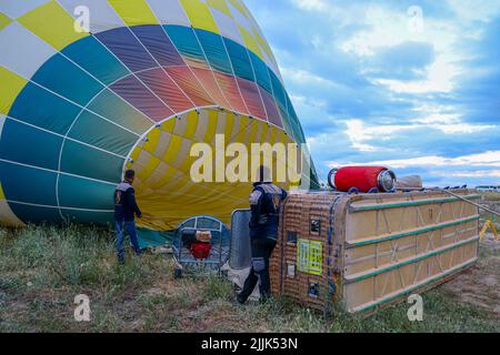 GOREME/TURCHIA - 26 giugno 2022: Gli uomini gonfiano la mongolfiera per prepararsi al volo turistico. Turchia. Foto Stock