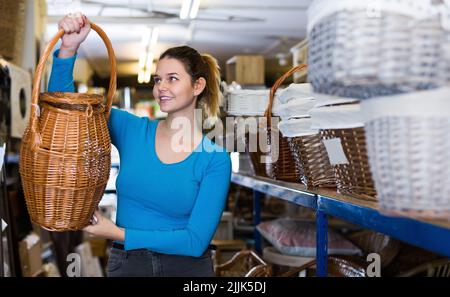 Giovane donna che osserva barile di vimini nel deposito di decorazione Foto Stock