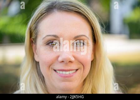 Donna di mezza età che guarda alla fotocamera con un'espressione felice in un primo piano Foto Stock
