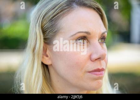 Donna bionda premurosa che guarda fino al lato musing un problema all'aperto in un colpo della testa di primo piano Foto Stock
