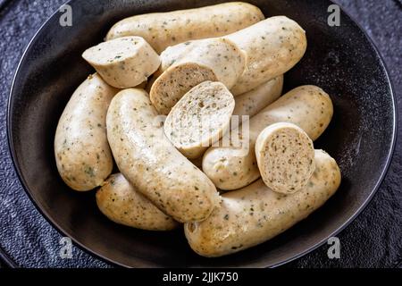 Weisswurst, salsicce bavaresi bianche di vitello tritato, pancetta di maiale, spezie e prezzemolo in ciotola nera, primo piano Foto Stock