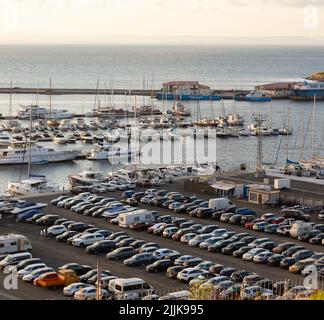 Una bella foto di un porto pieno di barche e di un parcheggio pieno di auto