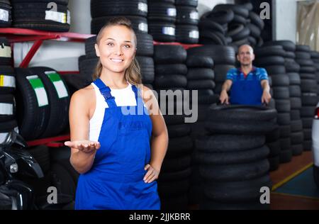 tecnico donna in tute in piedi in officina auto al coperto Foto Stock