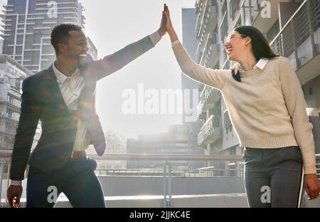 L'abbiamo fatto: Due giovani uomini d'affari si fidavano di più mentre si trovavano su un balcone per ufficio. Foto Stock