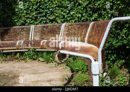 Primo piano di arrugginite panchine in metallo in cerchio senza persone in un parco. Non ci sono persone o marchi nella foto. Foto Stock