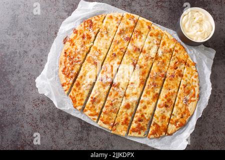 Dita all'aglio fatte in casa con mozzarella, pancetta e burro alle erbe e salsa Donair da vicino su carta sul tavolo. Vista dall'alto orizzontale dall'alto Foto Stock