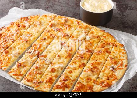 Pizza dita aglio con mozzarella, pancetta e burro di erbe e Donair Sauce primo piano su carta sul tavolo. Orizzontale Foto Stock