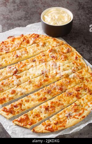 Deliziose dita all'aglio con burro alle erbe e mozzarella fusa spicchio di formaggio sulla carta sul tavolo. Verticale Foto Stock