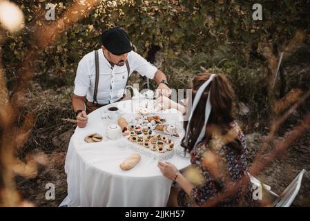 Una bella coppia caucasica a pranzo in un vigneto Foto Stock