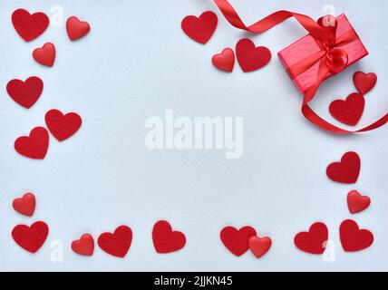 San Valentino sfondo. Confezione regalo rossa con nastro e cuori su sfondo blu pastello. Vista dall'alto Foto Stock