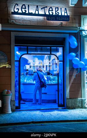 Una foto verticale di un negozio di gelateria illuminato blu a Castiglioncello, Italia Foto Stock