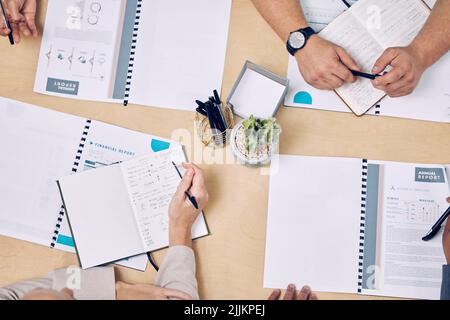 L'informazione è fondamentale per il successo. Colpo ad angolo alto di un gruppo di uomini d'affari irriconoscibili che guardano sopra il lavoro di ufficio mentre si siede intorno a. Foto Stock