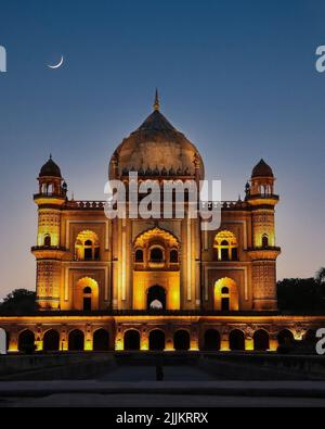 Una splendida foto verticale della tomba di Safdarjung con una luna a mezzaluna luminosa nel cielo blu e rosa sopra di essa Foto Stock