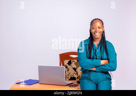 Un ritratto di una felice donna d'affari africana sorridente seduta con braccia incrociate davanti alla sua scrivania Foto Stock