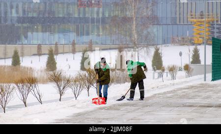 Minsk, Bielorussia - 21 gennaio 2022: I lavoratori rimuovono la neve dal marciapiede Foto Stock