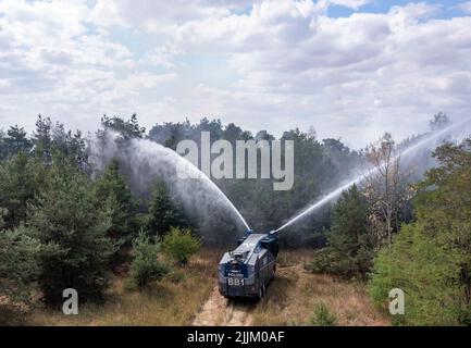 Falkenberg, Germania. 27th luglio 2022. Un cannone d'acqua della polizia di Brandeburgo estingue un incendio nella foresta. I vigili del fuoco di Brandeburgo continuano a combattere un grande incendio boschivo nel distretto di Elbe-Elster. Da lunedì (25.07.2022) brucia su una superficie di 800 ettari. Le aree sono parzialmente contaminate da munizioni. Questo complica il lavoro di estinzione degli incendi. (Vista aerea con un drone) Credit: Jan Woitas/dpa/Alamy Live News Foto Stock