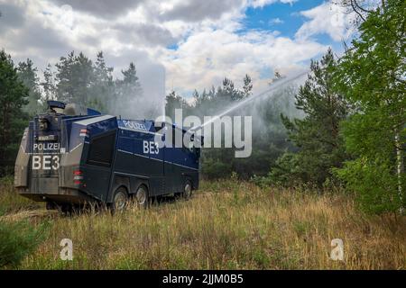 Falkenberg, Germania. 27th luglio 2022. Un cannone d'acqua della polizia di Brandeburgo estingue un incendio nella foresta. I vigili del fuoco di Brandeburgo continuano a combattere un grande incendio boschivo nel distretto di Elbe-Elster. Da lunedì (25.07.2022) brucia su una superficie di 800 ettari. Le aree sono parzialmente contaminate da munizioni. Questo complica il lavoro di estinzione degli incendi. Credit: Jan Woitas/dpa/Alamy Live News Foto Stock