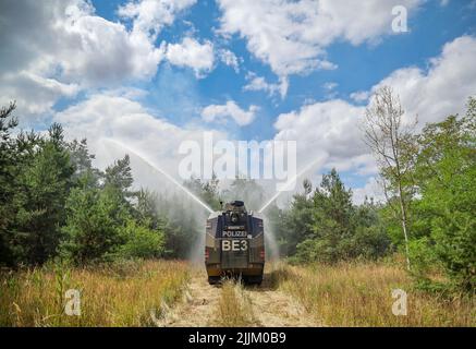 Falkenberg, Germania. 27th luglio 2022. Un cannone d'acqua della polizia di Brandeburgo estingue un incendio nella foresta. I vigili del fuoco di Brandeburgo continuano a combattere un grande incendio boschivo nel distretto di Elbe-Elster. Da lunedì (25.07.2022) brucia su una superficie di 800 ettari. Le aree sono parzialmente contaminate da munizioni. Questo complica il lavoro di estinzione degli incendi. Credit: Jan Woitas/dpa/Alamy Live News Foto Stock