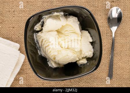 Diverse cialde di gelato bianco in un piatto di ceramica nera su un panno di iuta, macro, vista dall'alto. Foto Stock