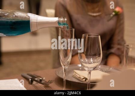 Un primo colpo di un liquido blu che viene versato in un bicchiere Foto Stock