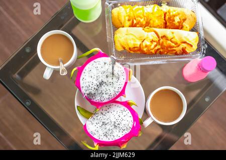 Colazione al mattino per due al tavolo. Dragon Fruit, caffè e panini, vista dall'alto. Foto Stock