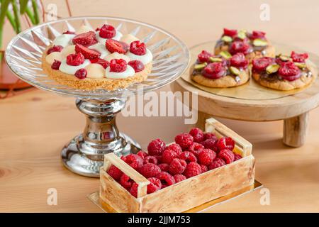 Pasticceria con panna e bacche. Cesti da forno con bacche fresche. Biscotti fatti in casa con lamponi. Foto Stock