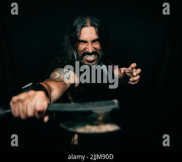 Ritratto di un Guerriero Vichingo ispanico che regge un'ascia nel New Jersey con sfondo nero Foto Stock