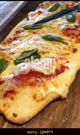 Dettaglio della pizza italiana fatta in casa con formaggio e pomodoro su un piatto di legno. Foto di alta qualità Foto Stock