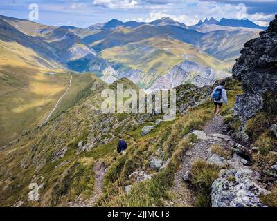 Una vista aerea di due persone con zaini a piedi su alte montagne rocciose con cielo blu all'orizzonte Foto Stock