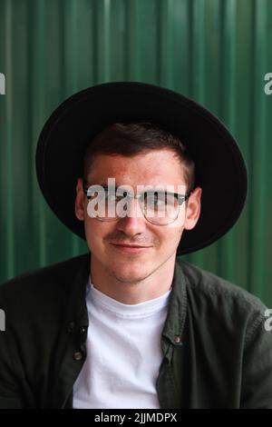 Buon uomo intelligente. Ritratto di bello sorridente elegante Hipster modello Lamberseual. Uomo vestito di occhiali e cappello nero. Maschio sul backgrou moderno Foto Stock