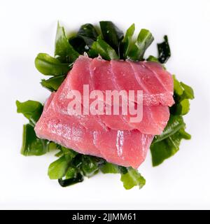Una vista dall'alto del tonno sashimi sul wakame su sfondo bianco Foto Stock