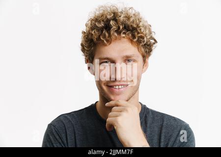 Giovane biondo con capelli ricci sorridente e guardando la macchina fotografica isolata sopra la parete bianca Foto Stock